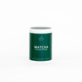 Green container of matcha powder with white lid on a white background