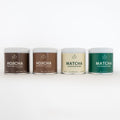 Four containers of different types of green tea powder on a white background