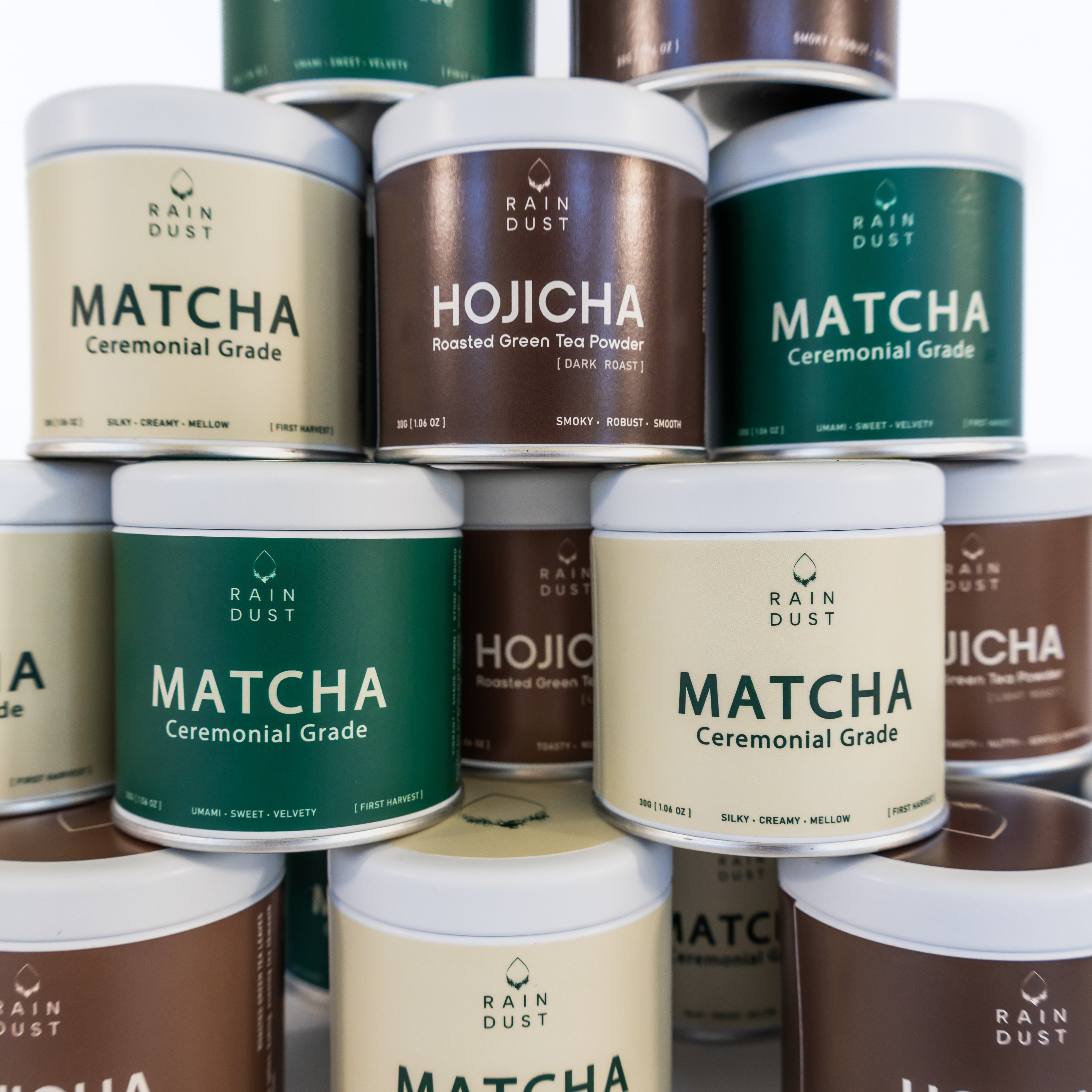 Stack of Rain Dust Matcha and Hojicha tea containers on a white background
