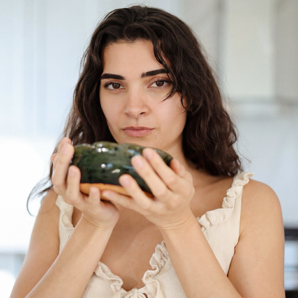 Woman holding a ceramic matcha bowl in front of her face while enjoying a Rain Dust ceremonial grade Japanese matcha ritual.